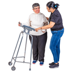 A person holding a walker with another person supporting them. This supporting person has one hand on the person with the walker's back and the other hand is on the walker. 